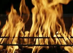 Flames rising over a metal grill grate against a dark background