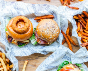 Two gourmet burgers and sweet potato fries on parchment paper
