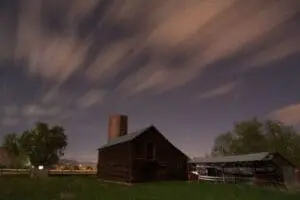 Abandoned farmhouse with brick chimney under night sky