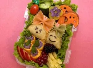 Creative food art platter with smiling potato faces and colorful vegetables on lettuce arranged on