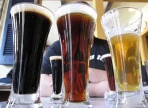 Five glasses of beer ranging from dark black to light amber in color