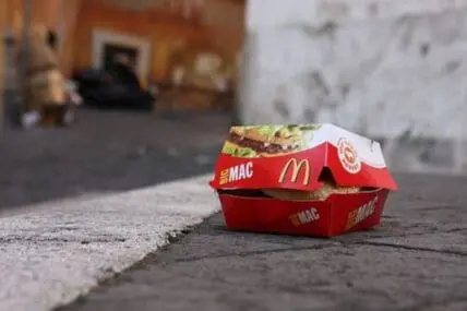 McDonald's Big Mac in red wrapper on pavement