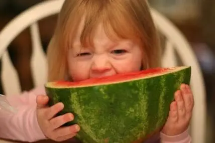 Toddler with red hair eating watermelon