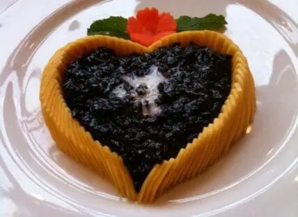 Heart-shaped tart with black rice filling and golden pastry crust, garnished with mint and red
