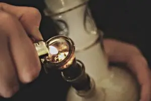 Close-up of hands holding a glass pipe with cannabis concentrate