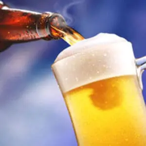 Beer being poured from a bottle into a glass against a blue background