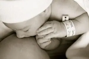 Newborn infant with hospital identification bracelet resting on parent's chest