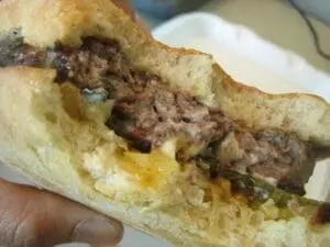 Close-up of a sandwich filled with shredded meat and melted cheese on a bun
