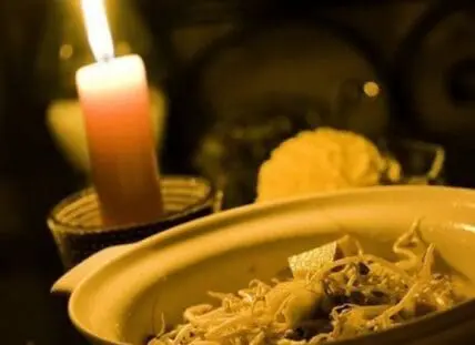 Candlelit plate of shredded food with burning candle in background
