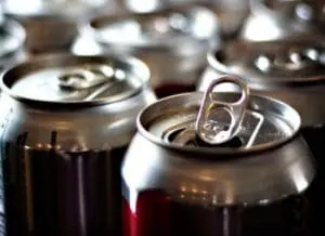 Close-up of open aluminum beverage cans with pull-tabs and dark liquid inside