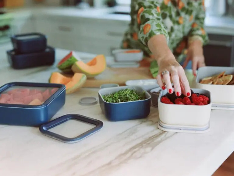 image of caraway food storage in use on countertop in cream and navy blue containers with hand reaching for berries.
