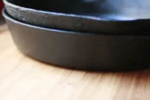 Cast iron skillet with rust and buildup on wooden surface
