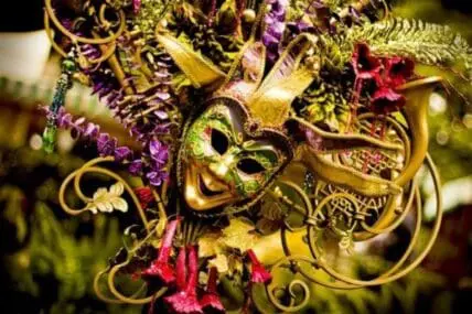 Ornate golden Mardi Gras masks decorated with purple, red, and green feathers