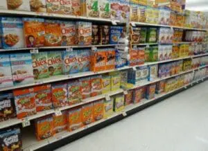 Supermarket shelf stocked with colorful cardboard cereal boxes