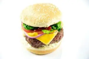 Cheeseburger with sesame seed bun, lettuce, tomato, and onion