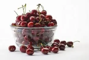 Fresh red cherries in a clear plastic container with stems