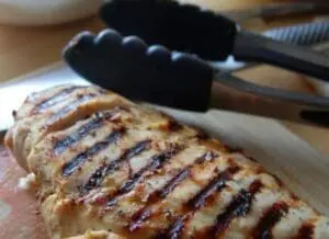 Grilled chicken breast with char marks on a cutting board