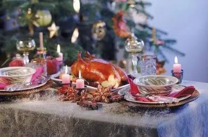 Elegant holiday table setting with roasted poultry, pink candles, and decorated Christmas tree