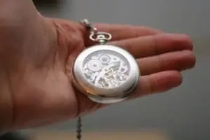 Silver pocket watch with exposed gears held in an open palm