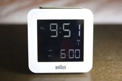 Braun digital alarm clock displaying 9:51 PM and 6:00 AM alarm time