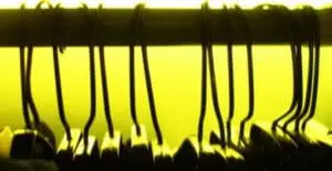 Black hangers hanging from a yellow rod against a bright yellow background.
