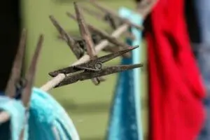 Wooden clothespins clipped to a clothesline with laundry in background