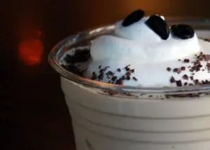 Whipped cream topped iced coffee drink with chocolate shavings and candy eyes