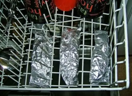 Three foil-wrapped fish fillets in a dishwasher rack