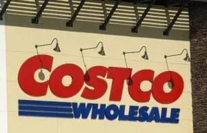 Costco Wholesale storefront sign with red letters and blue text on cream-colored wall