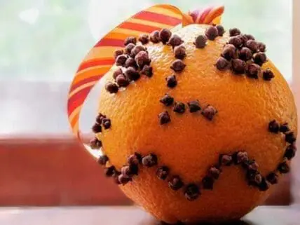 Orange decorated with cloves and a colorful ribbon bow as a DIY Halloween craft