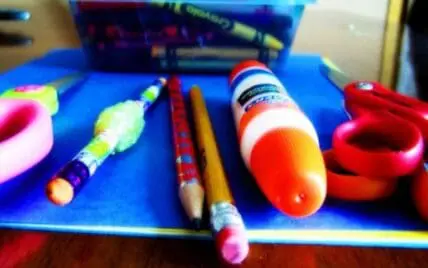 Colorful craft supplies including paintbrushes, markers, and decorative tape on a blue surface