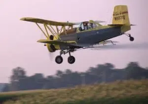 Crop duster airplane spraying agricultural chemicals over a field