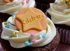 Chocolate cupcake with white frosting, colorful sprinkles, and a star-shaped cookie labeled