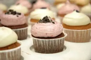 Chocolate cupcakes with pink and white frosting topped with cookie crumbles