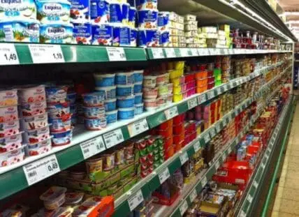 Refrigerated grocery store shelf displaying dairy and condiment products with price tags