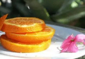 Sliced dekopon citrus fruit stacked on a white plate with a pink flower