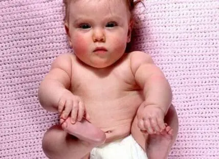 Infant wearing a diaper on a pink knitted blanket