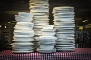Three stacks of white plates and bowls on a striped cloth surface