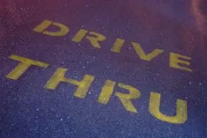 Yellow text reading "DRIVE THRU" on a purple pavement surface