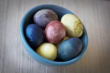 Naturally dyed Easter eggs in various colors in a blue bowl