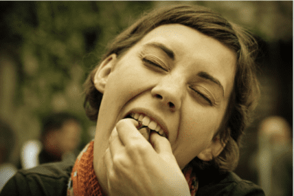 Woman with hand to mouth looking thoughtful about food choices