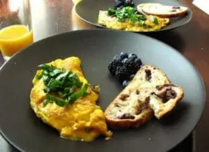 Breakfast plate with omelet, berries, and whole grain toast with orange juice