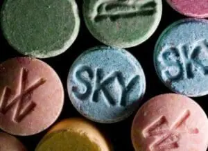 Colorful MDMA ecstasy pills with various markings on black background