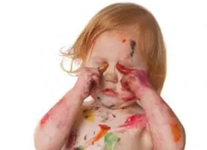 Toddler with paint and markers on face and hands