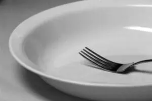 Empty white bowl with fork, symbolizing fasting and dietary restraint