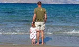 Father and daughter wading in the ocean together at the beach.