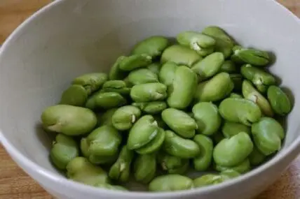 Fresh shelled fava beans in a white bowl