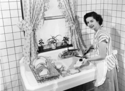 Woman washing dishes at a kitchen sink in a vintage black and white photograph