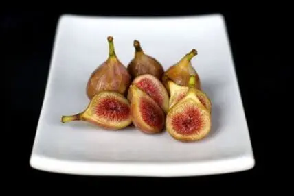 Fresh figs, whole and halved, arranged on a white plate