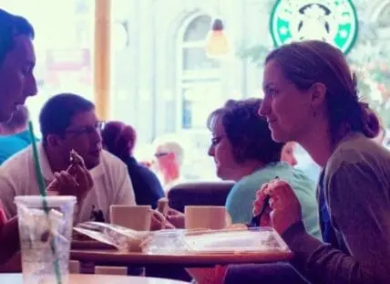 Group of people enjoying coffee and pastries together at a café table